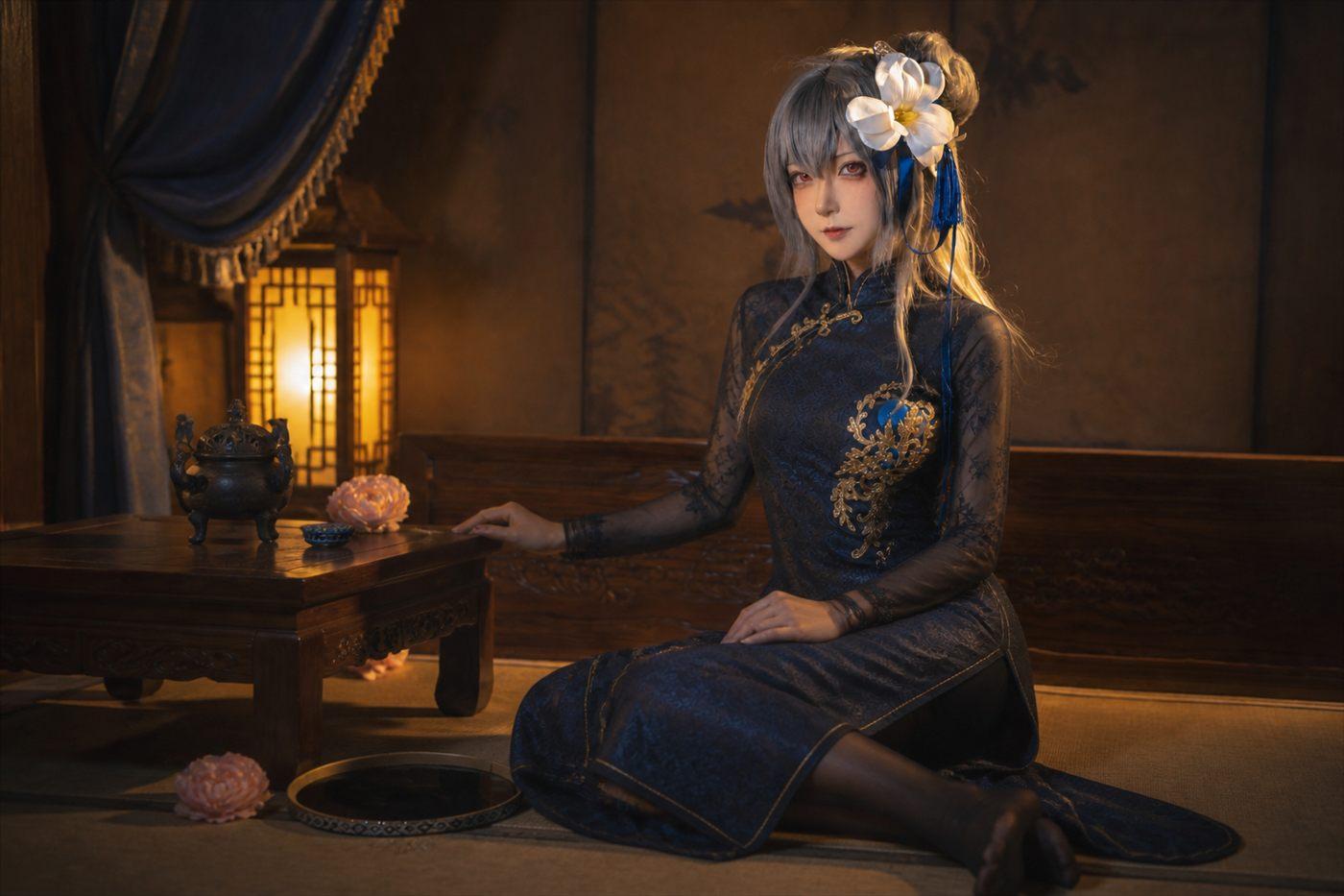 Seya狮砸路易九世身着完整深蓝旗袍坐在暖灯木榻与小桌旁的安全横幅场景