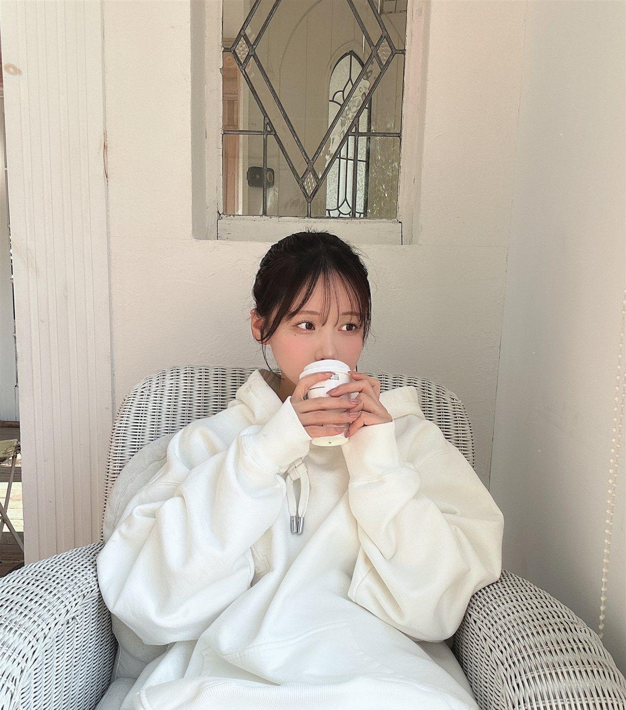 けん研穿白色宽松上衣捧纸杯